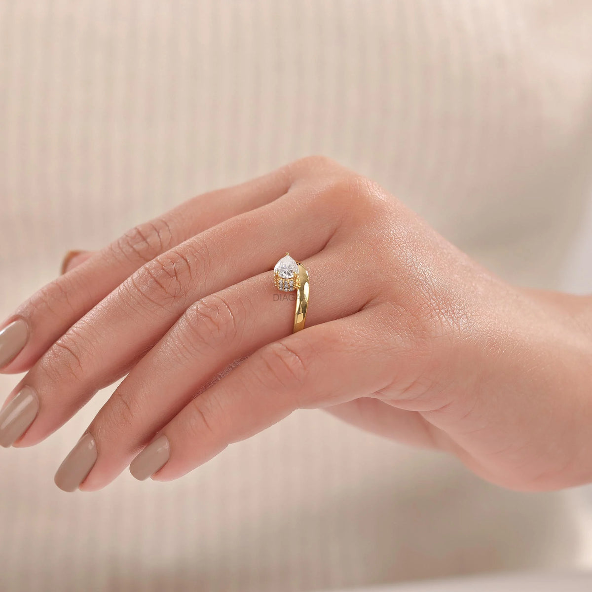 Woman wearing a 14K yellow gold Curve ring with Pear and round diamonds hidden vhalo ring