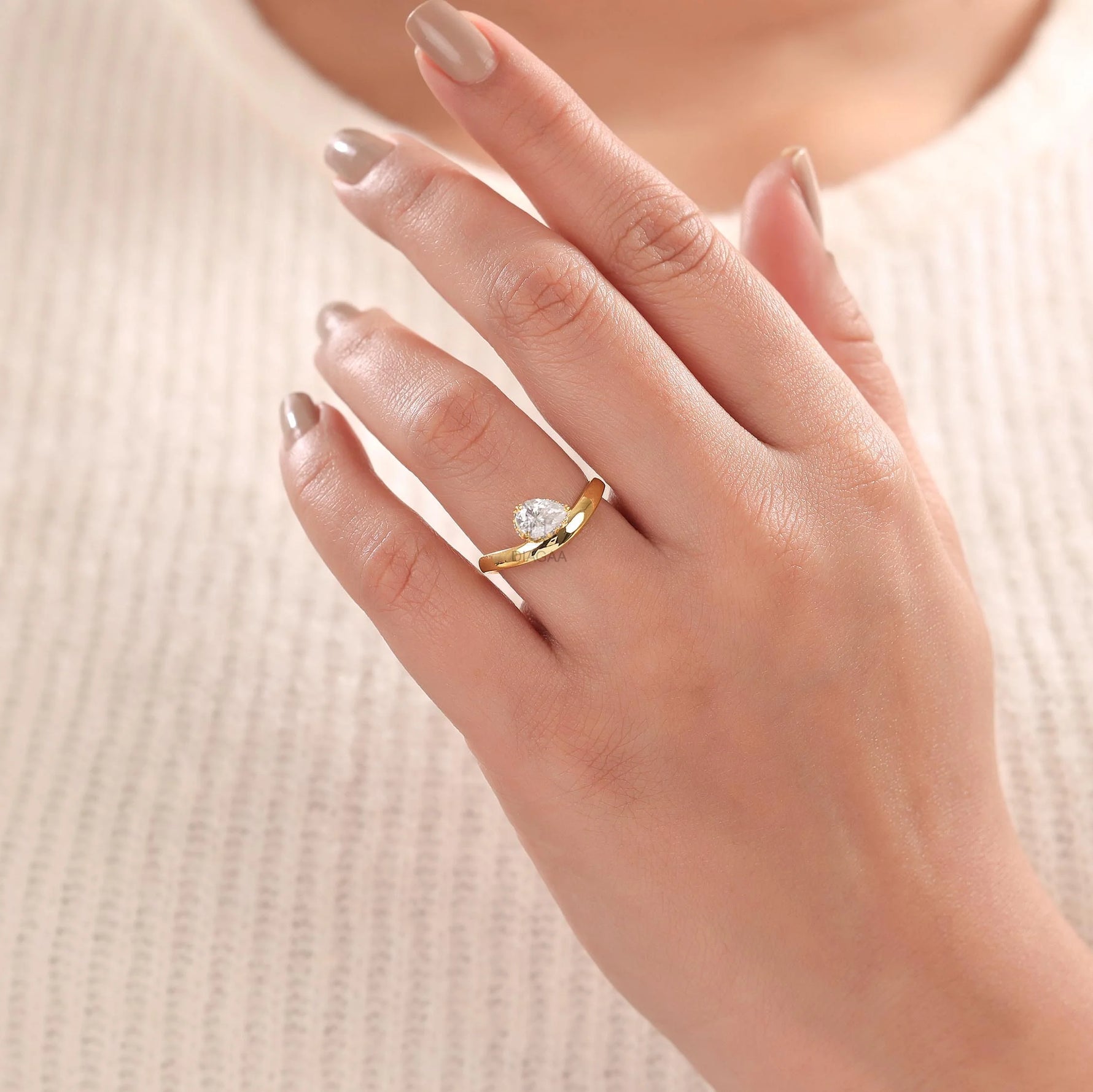 Woman wearing a 18K yellow gold Curve ring with Pear and round diamonds hidden vhalo ring