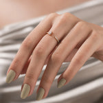 A hand modeling a delicate open gold ring featuring a pear-shaped diamond and a pave diamond band on the middle finger.