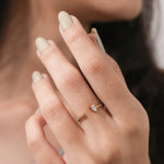 Gold open cuff ring featuring a pear-cut diamond and a pave diamond band on a woman's hand.