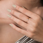 A delicate yellow gold open cuff ring with a pear and round diamond accent on a woman's middle finger.