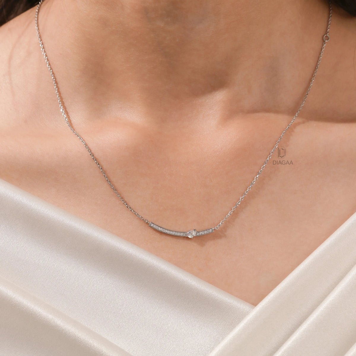 Woman wearing a delicate round and pear diamond necklace featuring prong and pave-set stones in white gold.