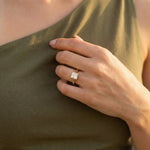 Minimalist yellow gold bezel solitaire ring featuring a square princess diamond, displayed gracefully on a woman’s ring finger for a clean bridal look.