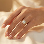 Woman wearing a yellow gold princess diamond solitaire engagement ring with a kite-set square diamond and halo set round diamond ring on her ring finger.