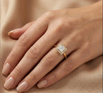 Woman wearing a 14k yellow gold princess diamond solitaire engagement ring with a kite-set square diamond and halo set round diamond ring on her ring finger.