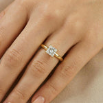 Close-up of a woman's hand wearing a classic yellow gold solitaire engagement ring featuring a square princess cut diamond on her ring finger.