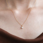 Model wearing a classic Round diamond necklace featuring a single prong-set solitaire pendant on a delicate 14K yellow gold chain.