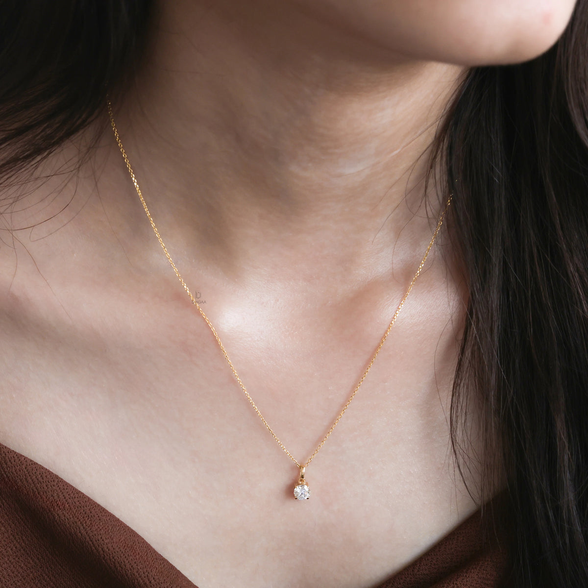 Model wearing a classic Round diamond necklace featuring a single prong-set solitaire pendant on a delicate 18K yellow gold chain.