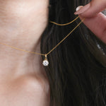 Close-up of a model wearing a delicate Round diamond necklace with a solitaire prong-set pendant in yellow gold.