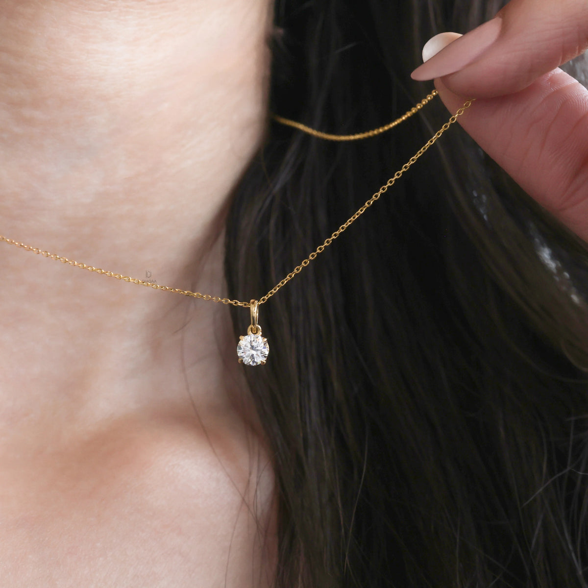 Close-up of a model wearing a delicate Round diamond necklace with a solitaire prong-set pendant in yellow gold.