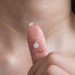 Model wearing a classic Round diamond necklace featuring a single prong-set solitaire pendant on a delicate yellow gold chain.