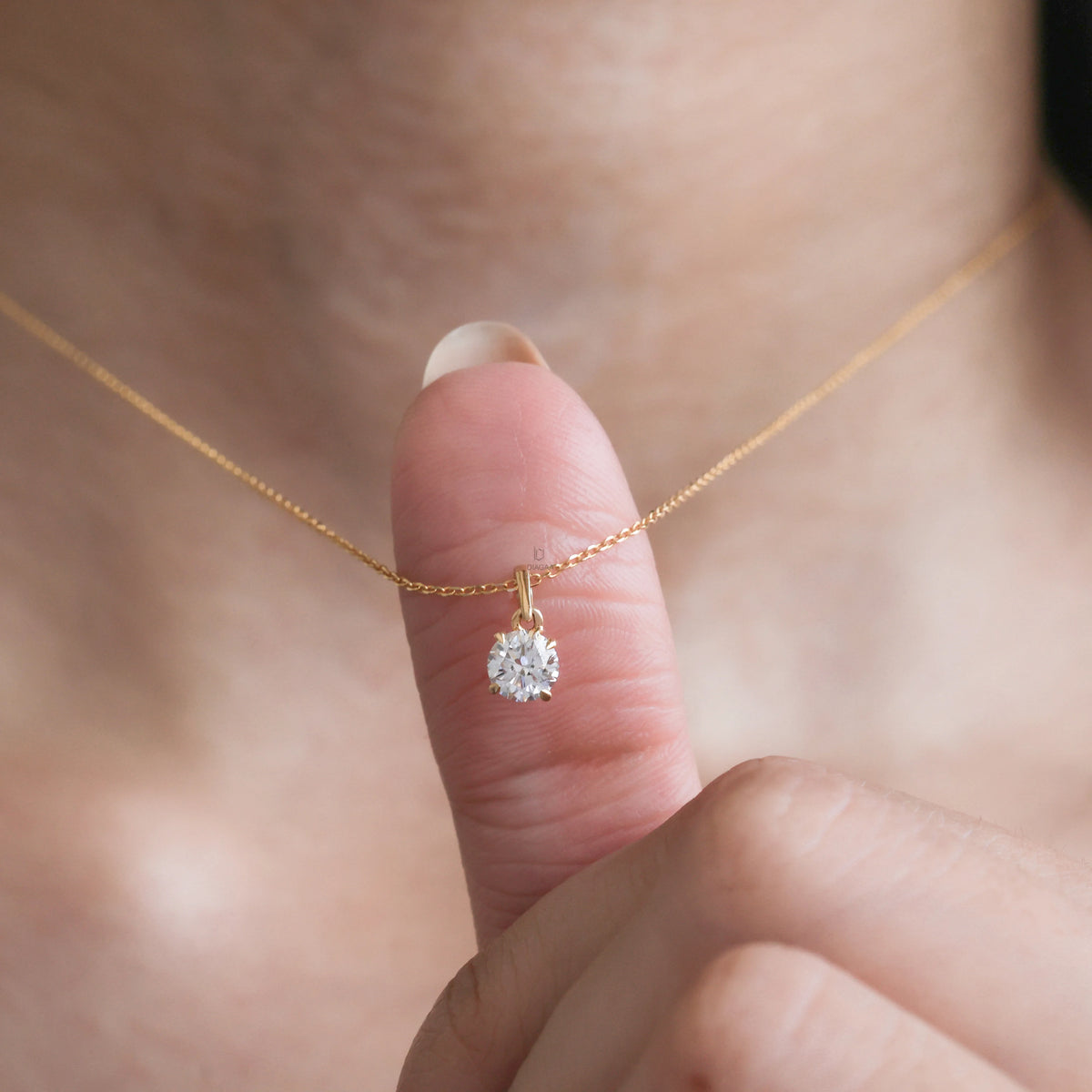 Model wearing a classic Round diamond necklace featuring a single prong-set solitaire pendant on a delicate yellow gold chain.