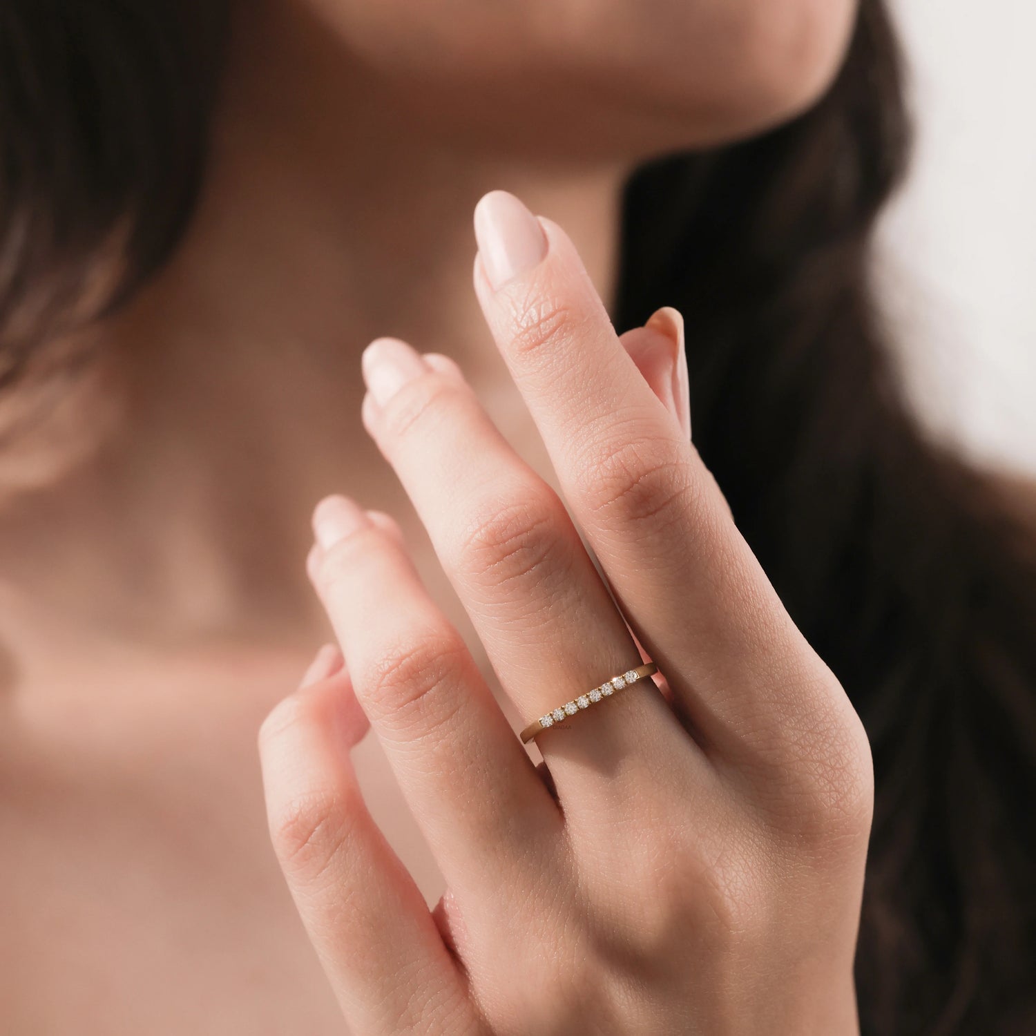A minimalist and elegant thin gold band with small round pavé diamonds, worn as a stacking ring.