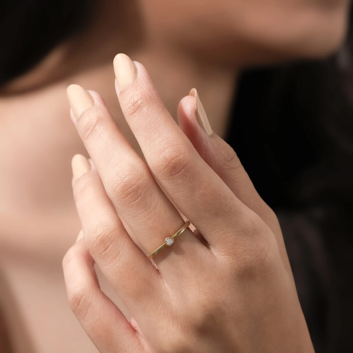 Dainty yellow gold solitaire ring with a small round diamond, modeled on a hand for a minimalist everyday jewelry look.