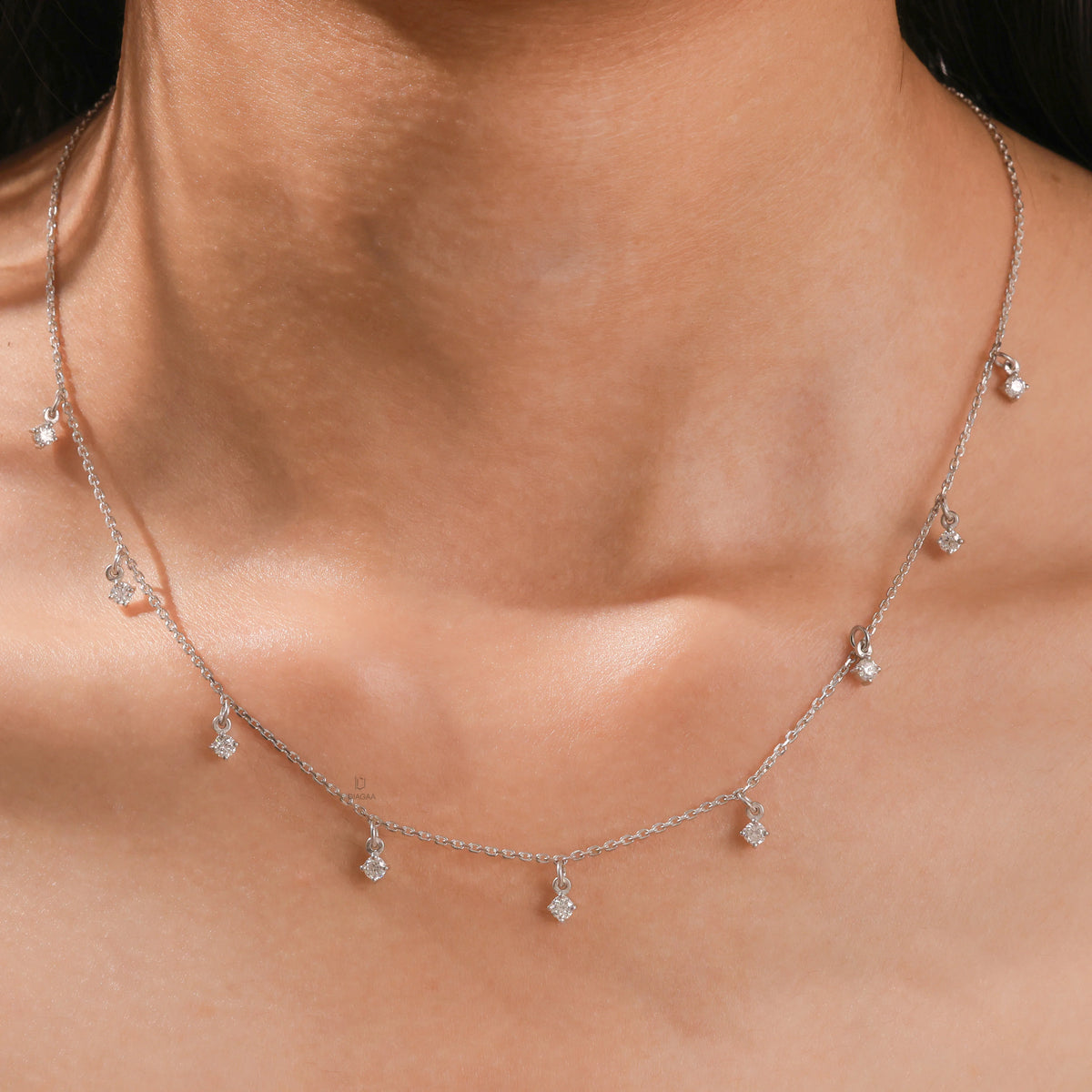 Model wearing a yellow gold Round diamond Dangling necklace featuring nine prong-set round diamond charms dangling along a fine chain.