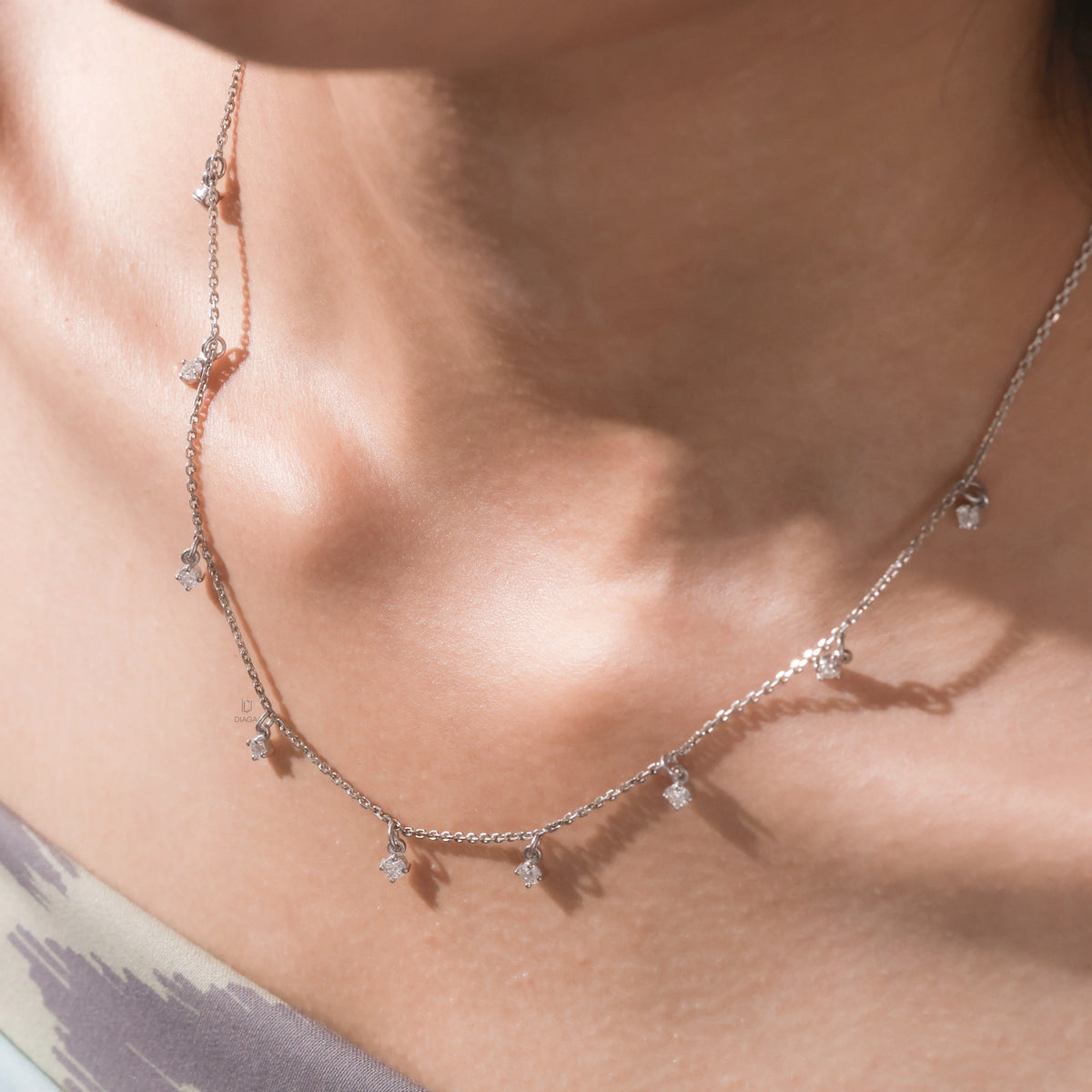 Model wearing a yellow gold Round diamond Dangling necklace featuring nine prong-set round diamond charms dangling along a fine chain.