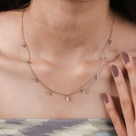 Model wearing a yellow gold Round diamond Dangling necklace featuring nine prong-set round diamond charms dangling along a fine chain.