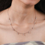 Model wearing a yellow gold Round diamond Dangling necklace featuring nine prong-set round diamond charms dangling along a fine chain.