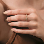 Close-up of a woman's hand wearing an elegant 14k yellow gold wrap ring with a modern split band and sparkling pavé set round diamond band 