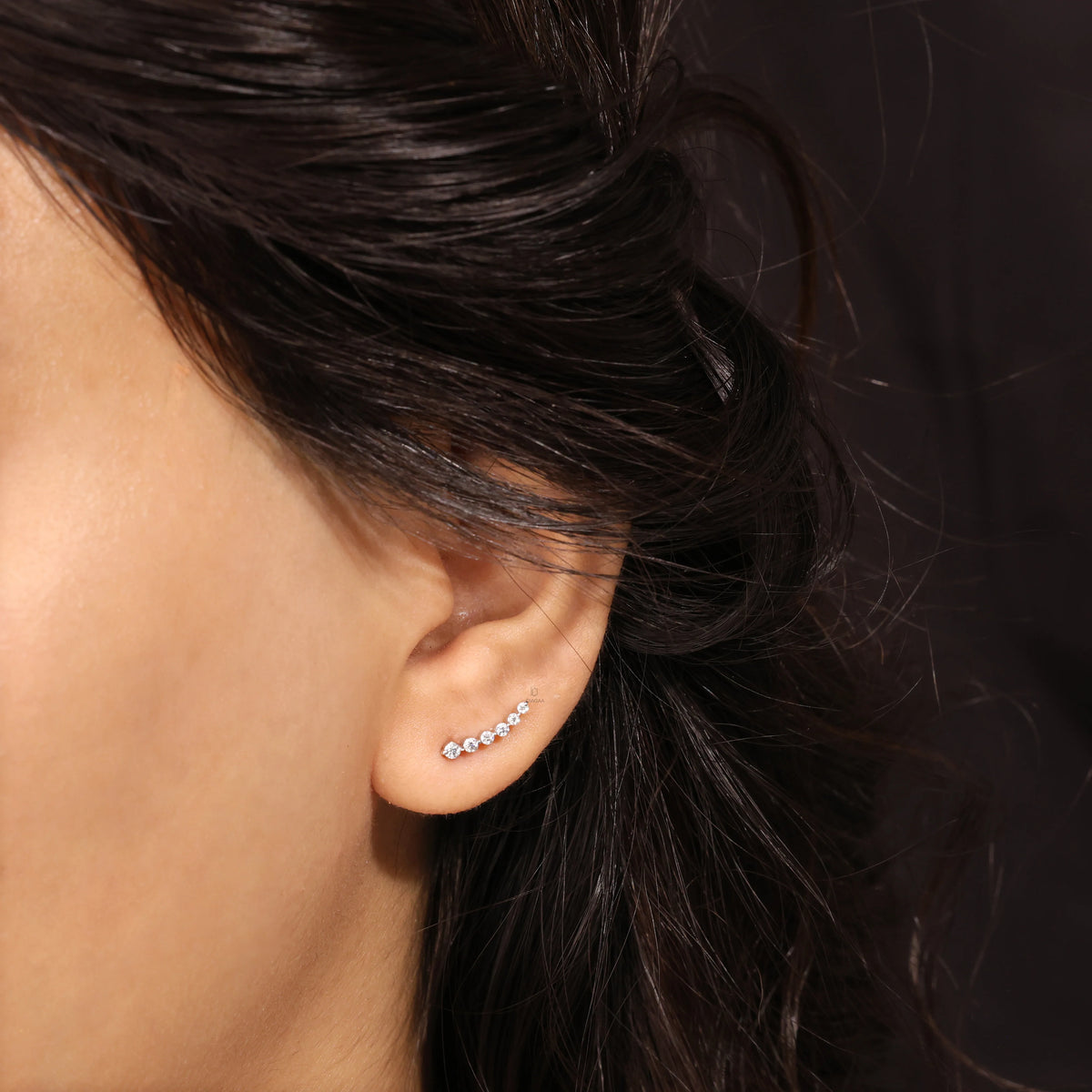 Curved climber-style round diamond stud earring styled along the earlobe, featuring aprong-setting and available in  10K yellow gold