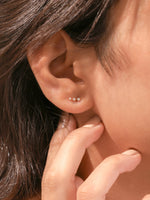 Modern white gold round diamond crawler earring styled along the natural curve of a model's earlobe to showcase real-world styling.