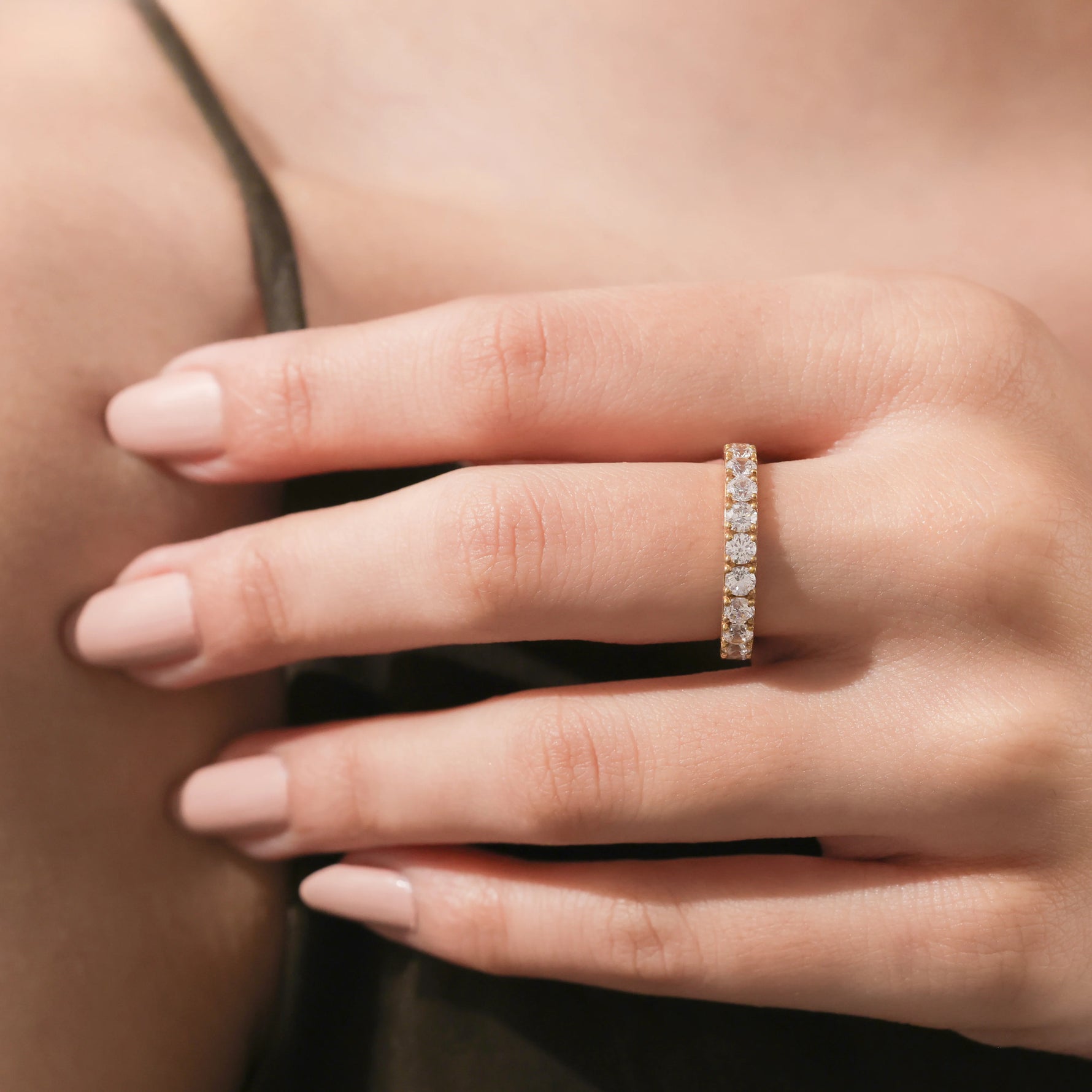 Elegant woman wearing a sparkling 14k yellow gold round diamond wedding ring, resting her hand lightly on her chin.