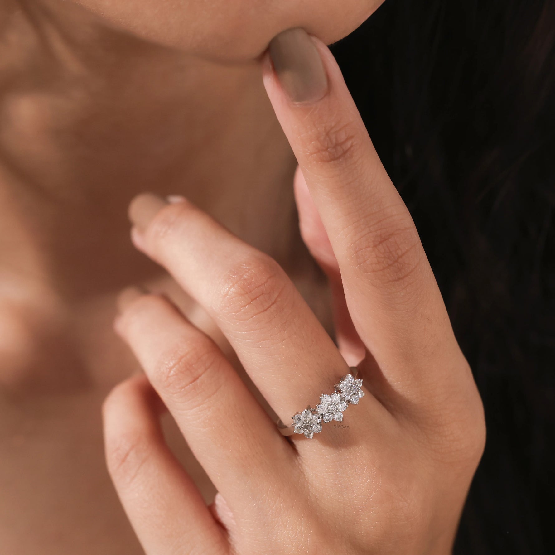 elicate 14k white gold round diamond cluster ring with an intricate three-flower motif worn on a woman's finger.