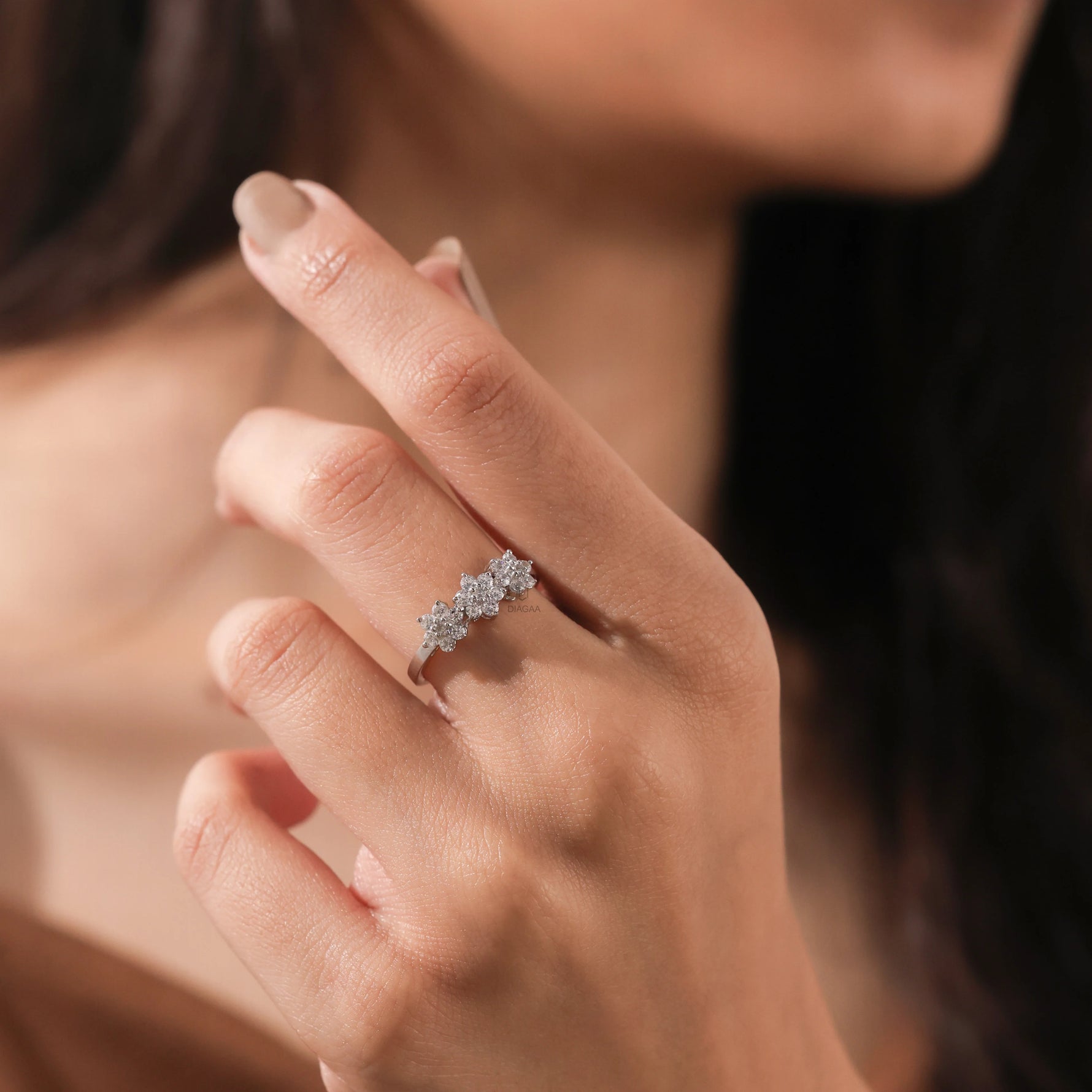 Woman wearing white gold round brilliant diamonds in a unique weddding ring featuring a sparkling three-flower floral cluster design on a smooth band