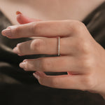 Close-up of a woman's hand wearing a delicate yellow gold diamond pave ring on her middle finger. Beautiful fine jewelry reference