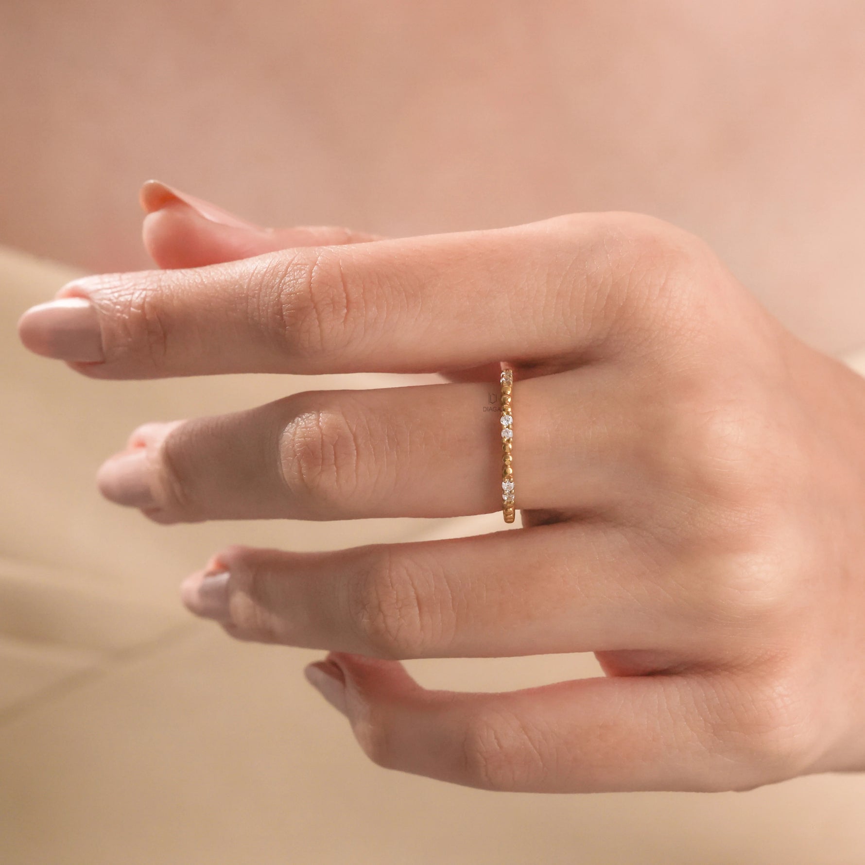 Modern yellow gold minimalist bubble band ring featuring round diamond wedding band, in a woman's hand wearing 