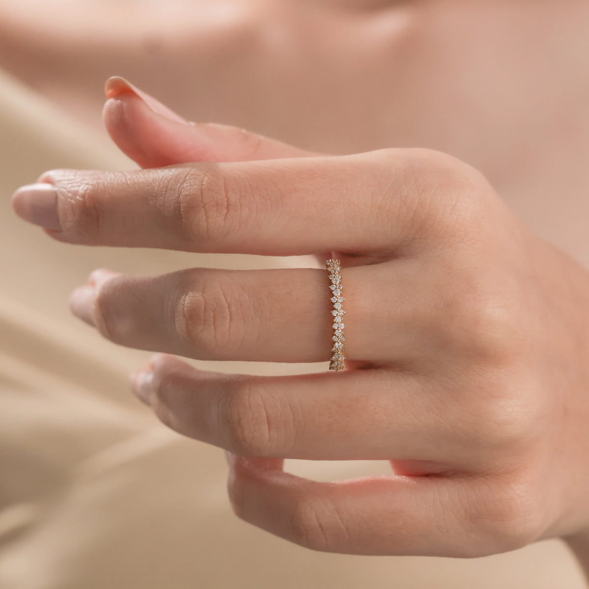 Elegant yellow gold half-eternity diamond ring with clustered stones, worn on a woman's finger against a soft neutral background.
