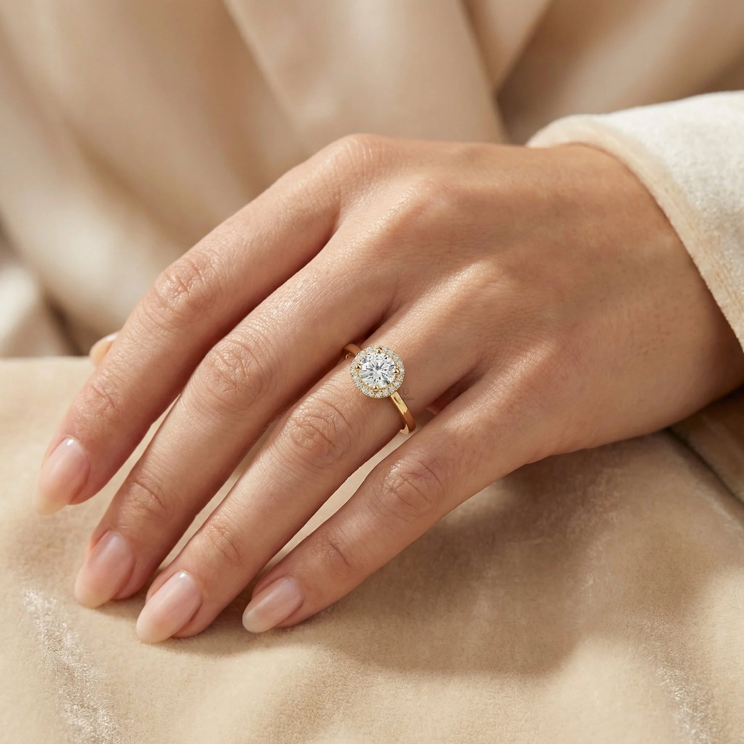 Close-up of a woman's hand wearing a brilliant round-cut diamond halo set engagement ring with a yellow gold band.