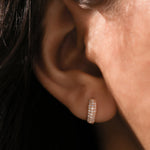 Elegant thick rose gold huggie hoop earring featuring multiple rows of sparkling pave diamonds modeled on an ear.