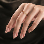 Delicate gold vine ring featuring dainty leaf motifs with diamond accents worn on a woman's hand.