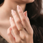 Close-up of a yellow gold diamond leaf ring on a woman's hand. Minimalist botanical wedding band and delicate twig jewelry.