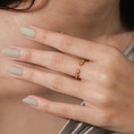 Gold open front ring featuring sparkling diamond accents worn on a finger. Delicate geometric stacking jewelry piece.