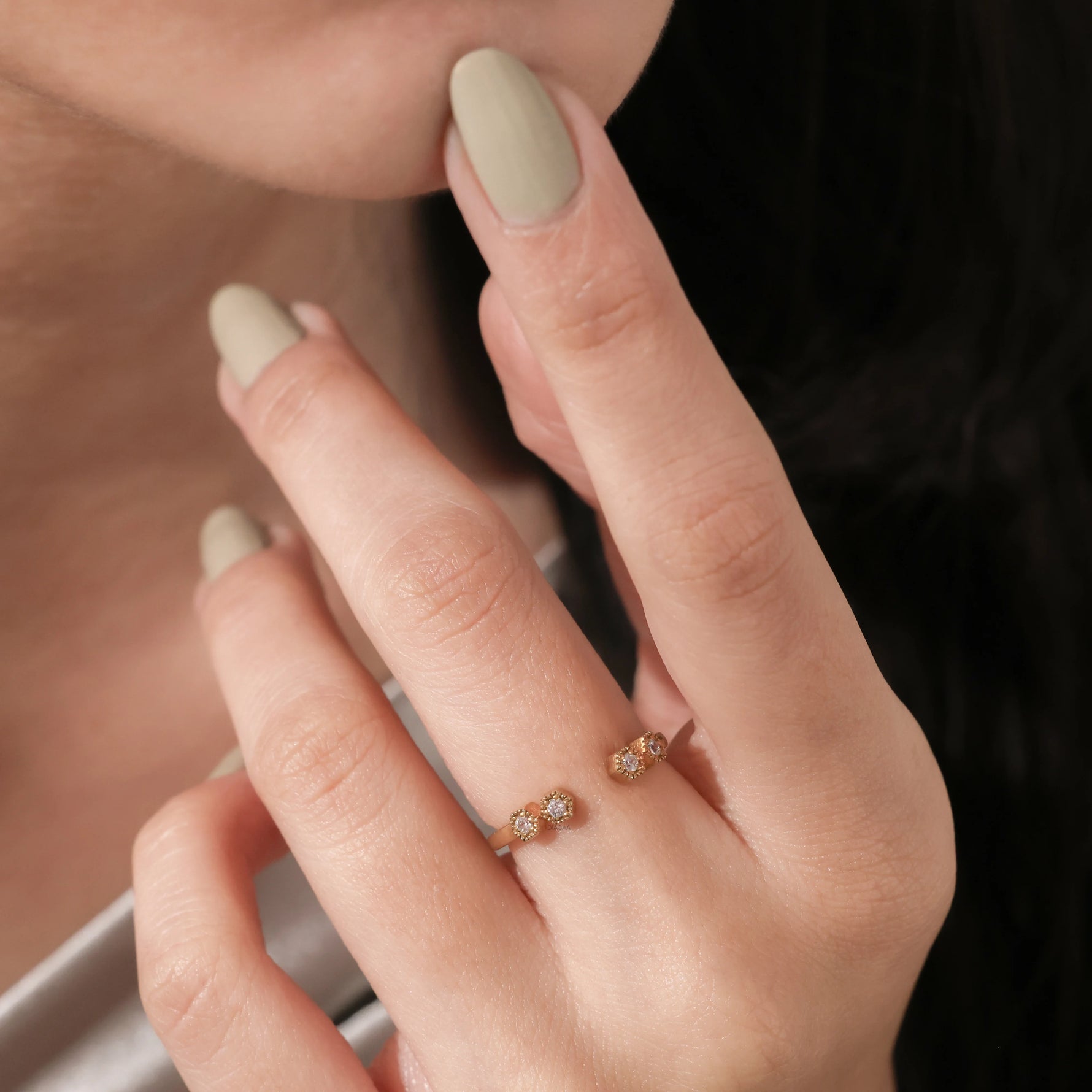 Model wearing a dainty gold open cuff ring with round diamonds on her finger. Elegant minimalist bypass stacking ring lifestyle photo. 