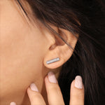 Vertical bar style round diamond stud earring styled on earlobe, featuring a sparkling pave setting in 18K white gold.