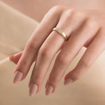 Woman wearing a thick yellow gold diamond band ring with a three-row pavé setting on her middle finger.
