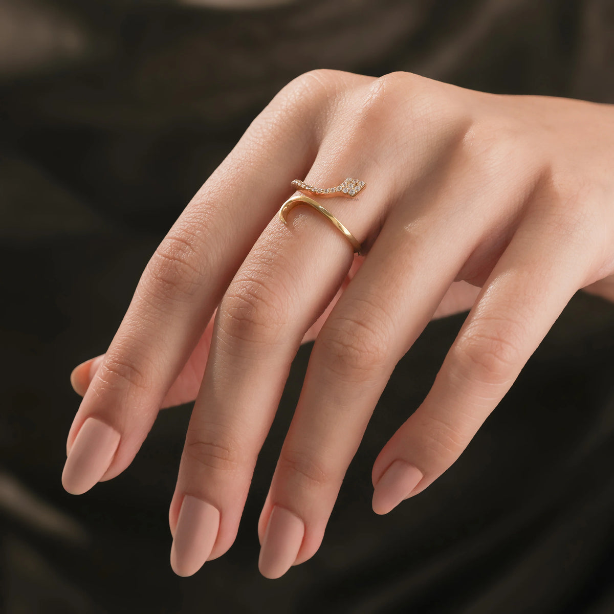 Model wearing a 14k yellow gold diamond snake ring on her ring finger, showcasing a modern round diamond minimalist wrap jewelry style.