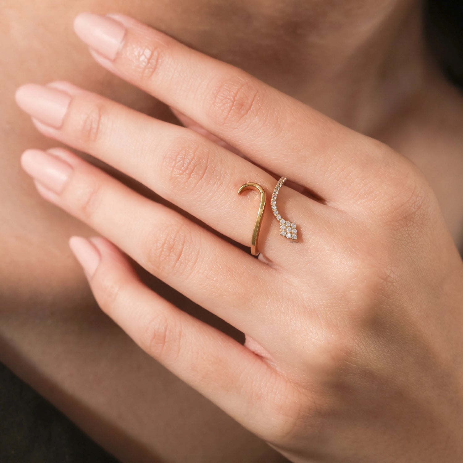 Woman modeling a delicate gold and diamond snake ring. This elegant wrap serpent ring features a sparkling pave diamond head and an adjustable open design.