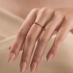 A woman wearing a dainty yellow gold stacking ring featuring a linear cluster of five small round diamonds.