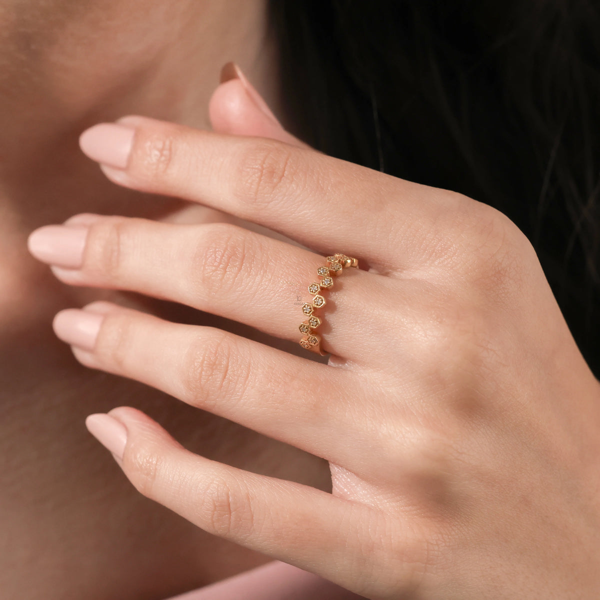 Dainty yellow gold ring featuring a geometric hexagon pattern set with brilliant diamonds, worn on a woman's finger for an elegant stacking looka.