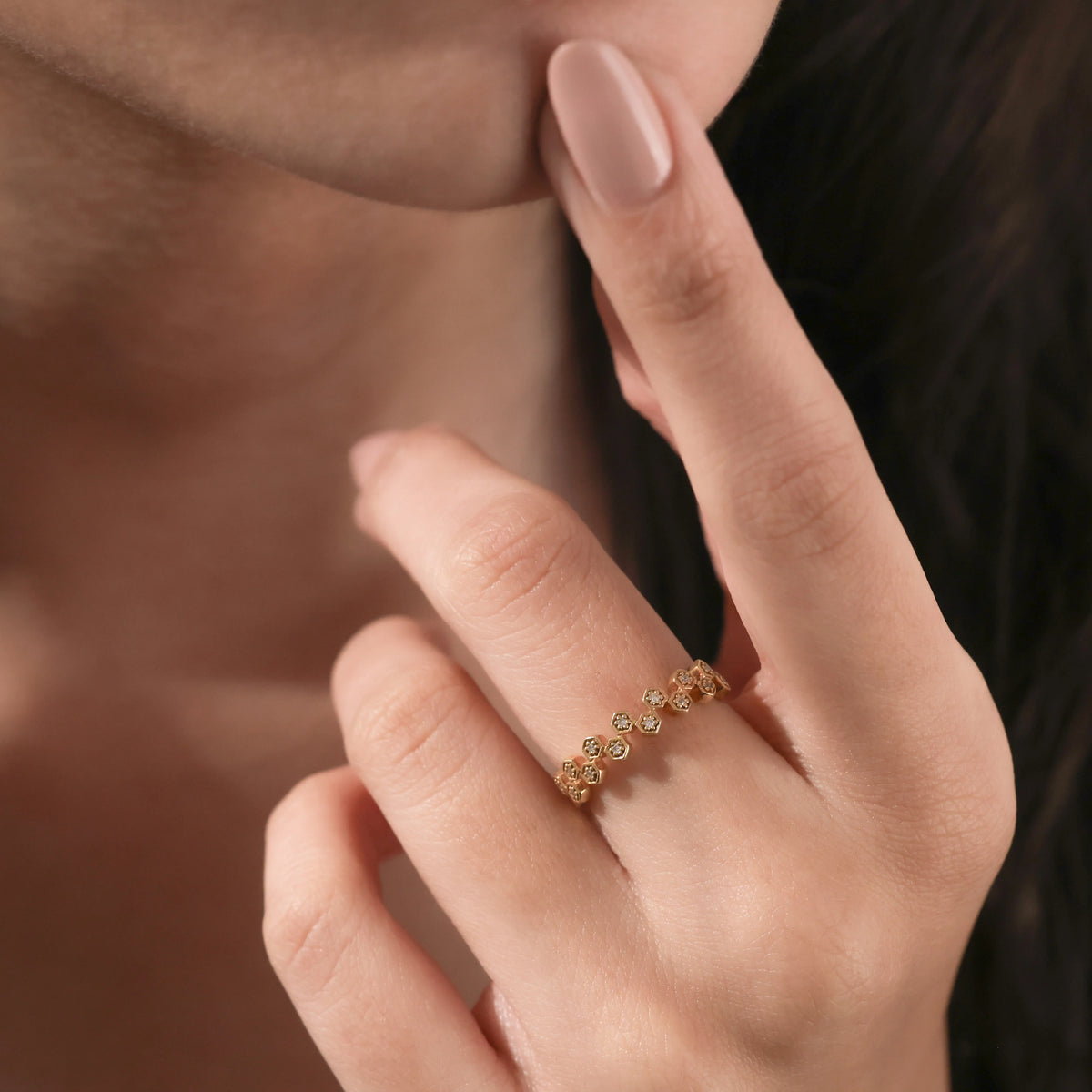 Close-up of a hand wearing a stylish zig zag wedding ring, styled as a chic round diamond yellow gold ring with bezel-set