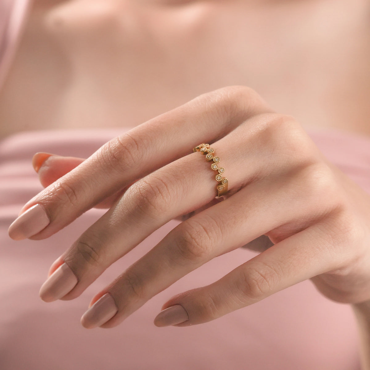 Close-up of a delicate yellow gold zig zag round diamond ring with diamonds on a woman's hand, showcasing a minimalist geometric stackable design.