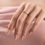 A minimalist gold crown stackable ring styled gracefully on a hand, highlighting a slim wedding band design with a curved row of small round diamonds.