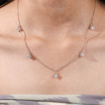 Model wearing a yellow gold Round diamond Dangling necklace featuring five prong-set round diamonds suspended along a delicate chain.