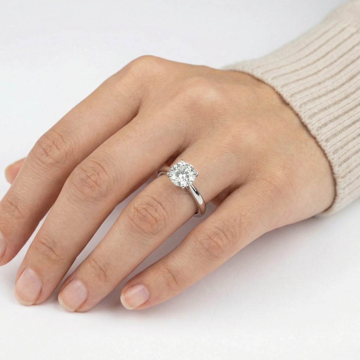 Woman wearing a classic round solitaire diamond engagement ring with a white gold band on her hand.