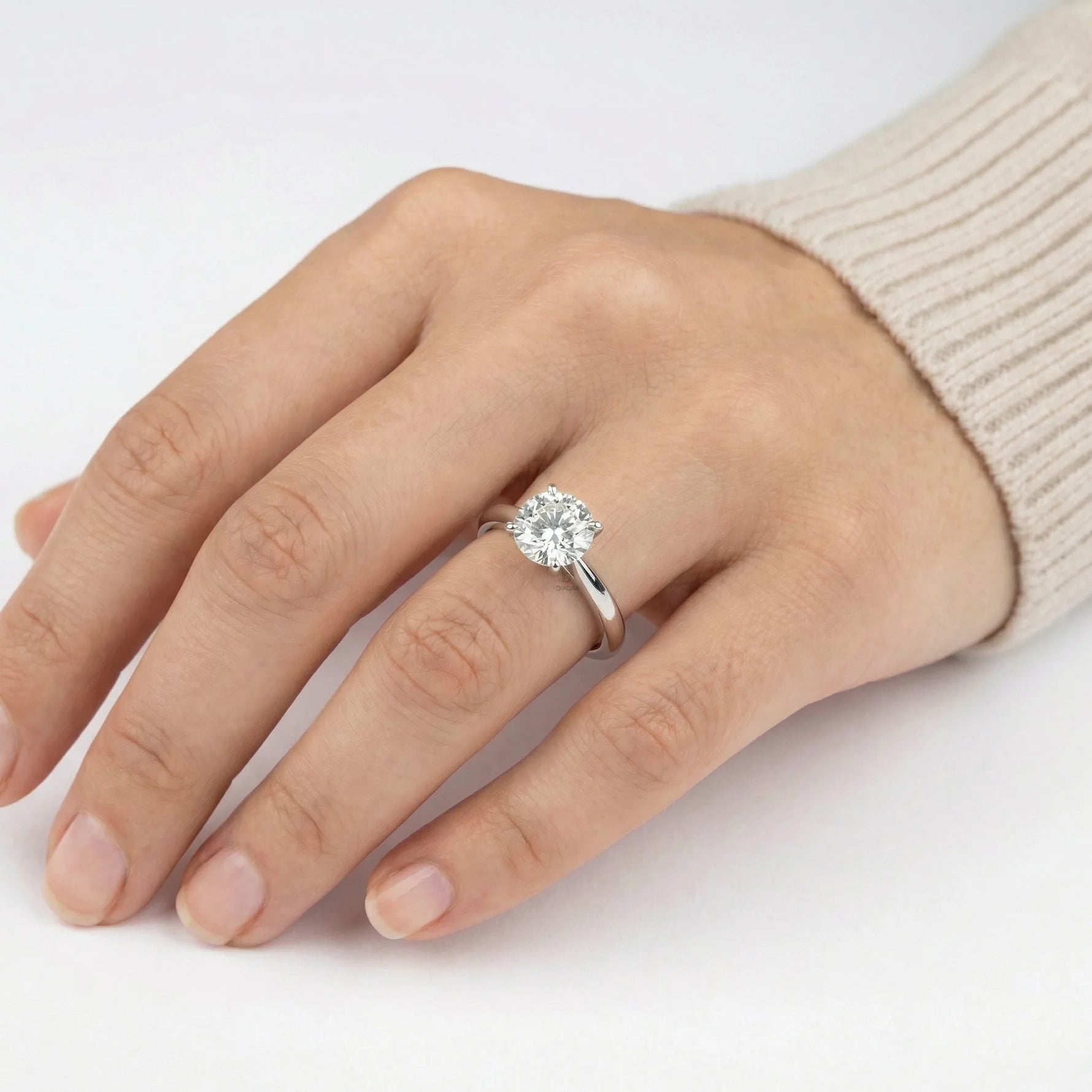 Woman wearing a classic round solitaire diamond engagement ring with a white gold band on her hand.