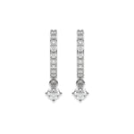 Solitaire round diamond dangling hoop earring set featuring a brilliant drop stone held in a white gold prong setting with white background.